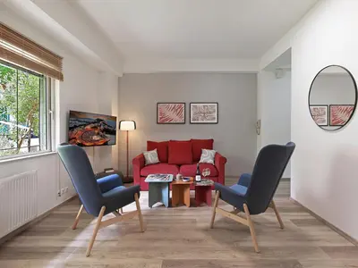 a living room with a red couch and two chairs at Prime Location in Kolonaki A Luxurious 1BR Haven in Athens