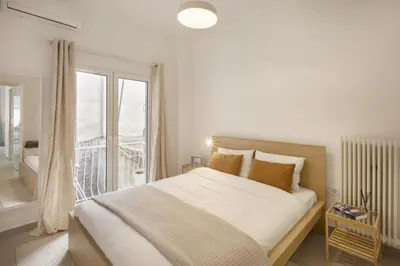 a white bedroom with a large bed and a balcony at Kerameikou25 large in Athens