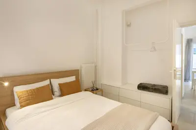 a white bedroom with a bed and a window at Kerameikou25 large in Athens