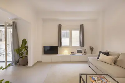 a white living room with a couch and a tv at Kerameikou25 large in Athens