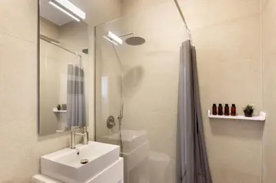 a white bathroom with a sink and a shower at Kerameikou25 small in Athens