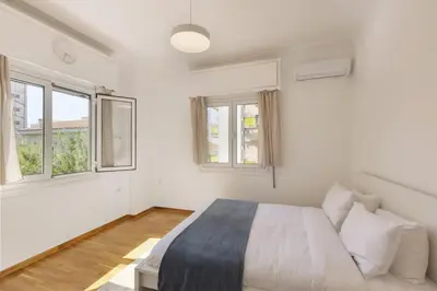 a white bedroom with a bed and two windows at Kerameikou25 small in Athens