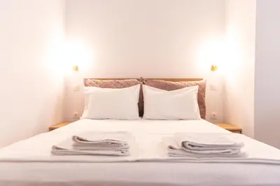 a bed with white sheets and white pillows at Harmony - Brand New Airport Apt. in Spáta