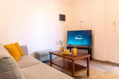 a living room with a couch and a table with a tv at Harmony - Brand New Airport Apt. in Spáta