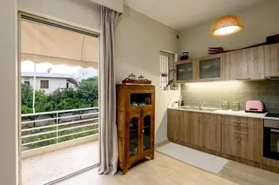 a kitchen with wooden cabinets and a large window at Quiet Family apartment with Garden and Balconies in Athens