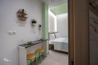 a small room with a bed and a table and stools at The Mint - Stylish Studio in Egaleo-Athens in Athens
