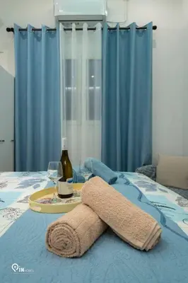 a table with a towel and a glass of wine on a bed at The Aqua - Stylish & Comfy Studio in Egaleo-Athens in Athens