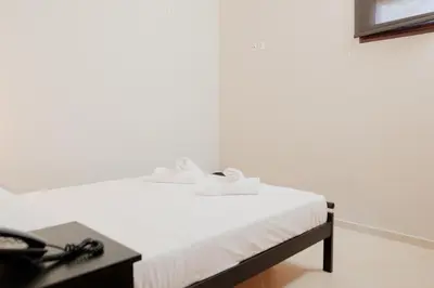 a bedroom with a bed with white sheets and a table at Villa GEM in Porto Rafti