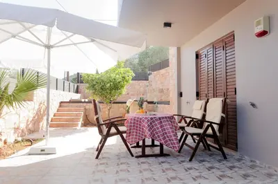 a patio with a table and chairs and an umbrella at Villa GEM in Porto Rafti