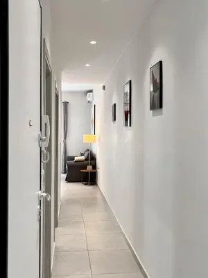 a hallway with white walls and a room with a couch at Chic Getaway Near Stavros Niarchos in Athens