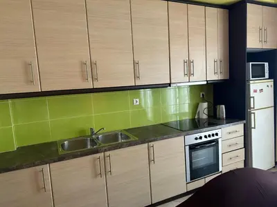 a kitchen with wooden cabinets and a sink and a refrigerator at Riviera Beach apart no 5 in Anavissos