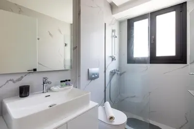 a white bathroom with a sink and a shower at Athens Sea Side Escape in Vari
