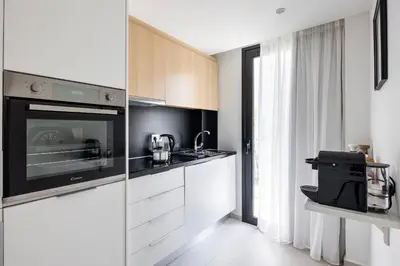 a kitchen with white cabinets and a black microwave at Athens Sea Side Escape in Vari
