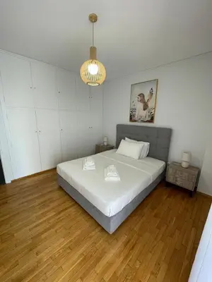 a bedroom with a large white bed and wooden floors at South coast -- AL020 in Athens