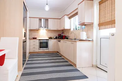 a kitchen with wooden cabinets and a blue and white rug at Koropi 3 bedroom Luxurious Apartment 5 pers- Angel House in Koropíon