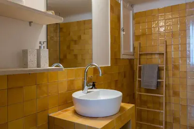 a bathroom with a white sink on a yellow tiled wall at Honey in Athens