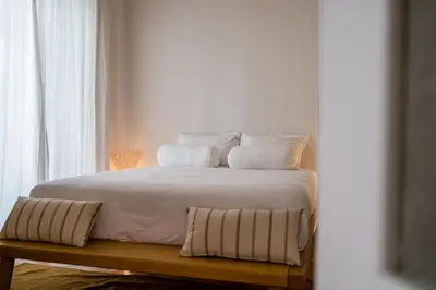 a white bed with white sheets and pillows on it at Honey in Athens