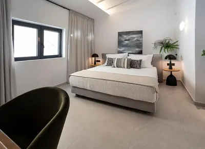 a white bedroom with a bed and a chair at Maison 36 Villa in the center of Psyri in Athens
