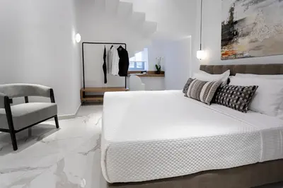 a white bedroom with a bed and a chair at Maison 36 Villa in the center of Psyri in Athens