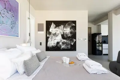 a bedroom with a white bed with a painting on the wall at Experience Penthouse by Athens Riviera Suites in Saronida