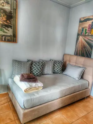 a couch with pillows on it in a room at Home4U, just 7km from airport in Markopoulo