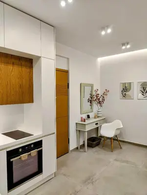 a white kitchen with a table and a chair at Elpis' cozy & luxury apartment in Athens