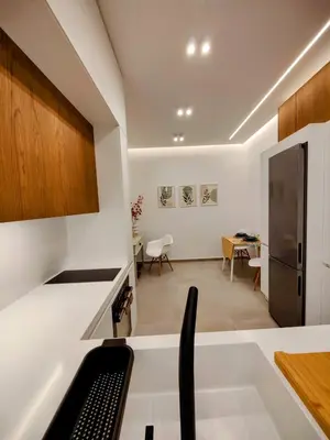 a kitchen and dining room with white walls and wood cabinets at Elpis' cozy & luxury apartment in Athens