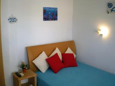 a bedroom with a bed with red and white pillows at Sunrise Flora in Agia Marina Aegina