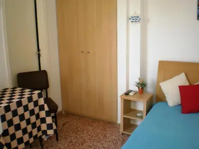 a bedroom with a bed and a table and a door at Sunrise Flora in Agia Marina Aegina