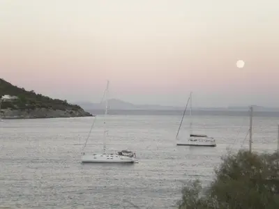 three boats in the water with the moon in the sky at Sunrise Flora in Agia Marina Aegina