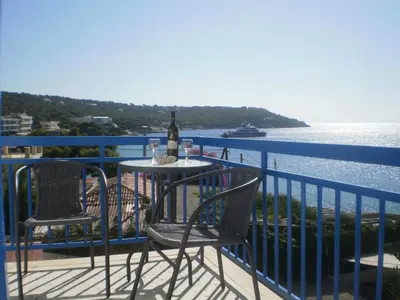 a table and chairs on a balcony with a bottle of wine at Sunrise Flora in Agia Marina Aegina