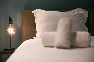 a bed with a white pillow and a lamp at Cocoon Athenian Riviera by Neuvel in Athens