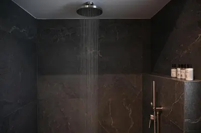 a bathroom with a shower with black tiles at Cocoon Athenian Riviera by Neuvel in Athens