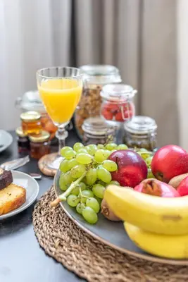 a plate of fruit on a table with glasses of orange juice at Acropolis Divine Apartments in Athens