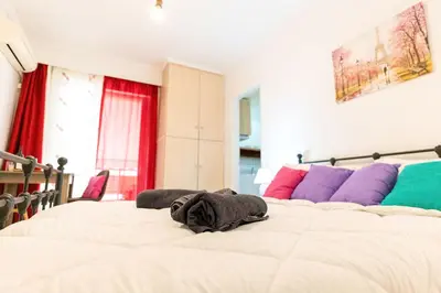a bedroom with two beds with white sheets and purple pillows at Maria's Apartment δίπλα στο Νοσοκομείο Παίδων και στο Λαϊκό in Athens