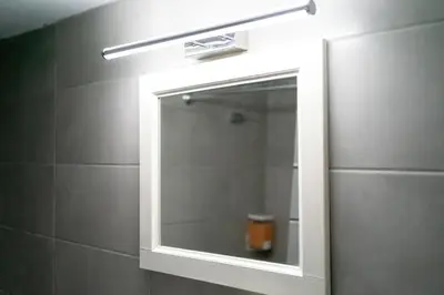 a bathroom mirror with a light above a shower at Maria's Apartment δίπλα στο Νοσοκομείο Παίδων και στο Λαϊκό in Athens