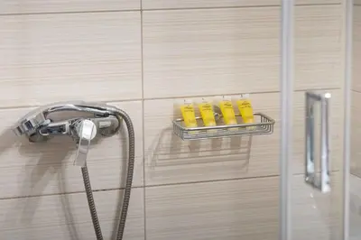 a shower head and a rack with four yellow objects at Waylink Residences - Piraeus Port DRB in Piraeus