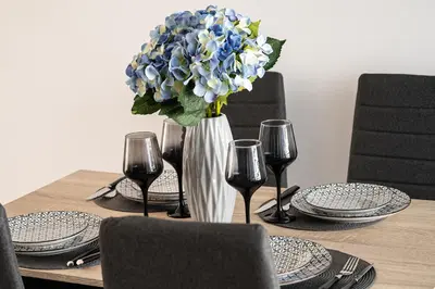 a table with a vase of blue flowers and wine glasses at Waylink Residences - Piraeus Port DRB in Piraeus