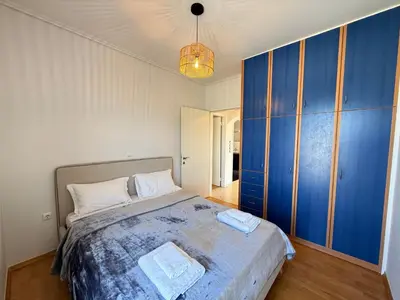 a bedroom with a large bed with blue cabinets at Sunny Home Private Jacuzzi Hydromassage, Fireplace, Acropolis & Lycabettus View, Underground Parking, 300m Metro Peristeri in Athens