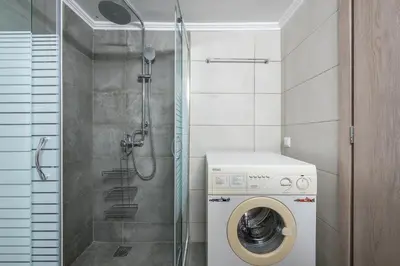 a bathroom with a washing machine and a shower at Stylish City Apartment by CloudKeys in Athens