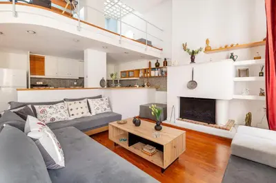 a living room with a gray couch and a fireplace at Athenian Getaway Villa in Plaka with Acropolis View by Athenian Homes in Athens