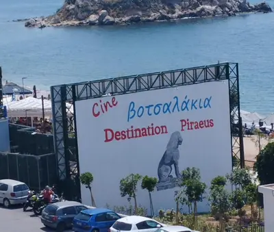 a sign in front of the ocean with cars parked at Mia's Seaside Penthouse - Panoramic View in Piraeus