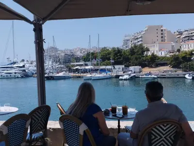 a couple sitting at a table overlooking a marina at Mia's Seaside Penthouse - Panoramic View in Piraeus