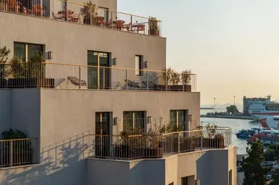 a building with chairs and plants on the balconies at Mitsis N'U Piraeus Port in Piraeus