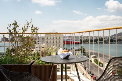a table on a balcony with a view of the water at Mitsis N'U Piraeus Port in Piraeus