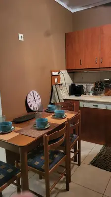 a kitchen with a wooden table and a clock on the wall at M&M Airport stop Garden Apartment in Spáta