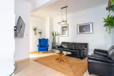 a living room with a black leather couch and a blue chair at Majestic 2 Glyfada in Athens