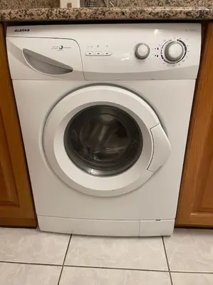 a white washing machine sitting under a counter at DM Apartment 1 in Athens