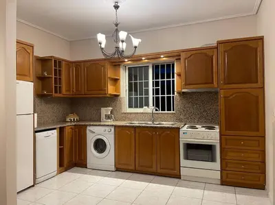a kitchen with wooden cabinets and a white dishwasher at DM Apartment 1 in Athens