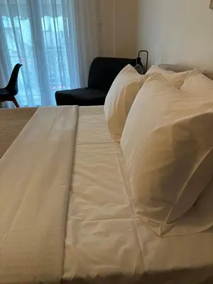 a large bed with white sheets and pillows at Cozy Faliro home in Piraeus